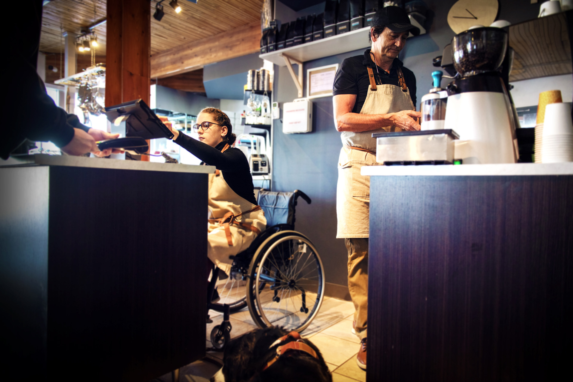 Une femme en fauteuil roulant encaisse le paiement derrière le bar